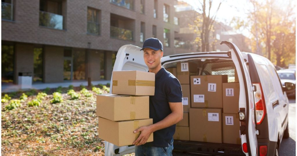 Man holding boxes standing outside his delivery van.